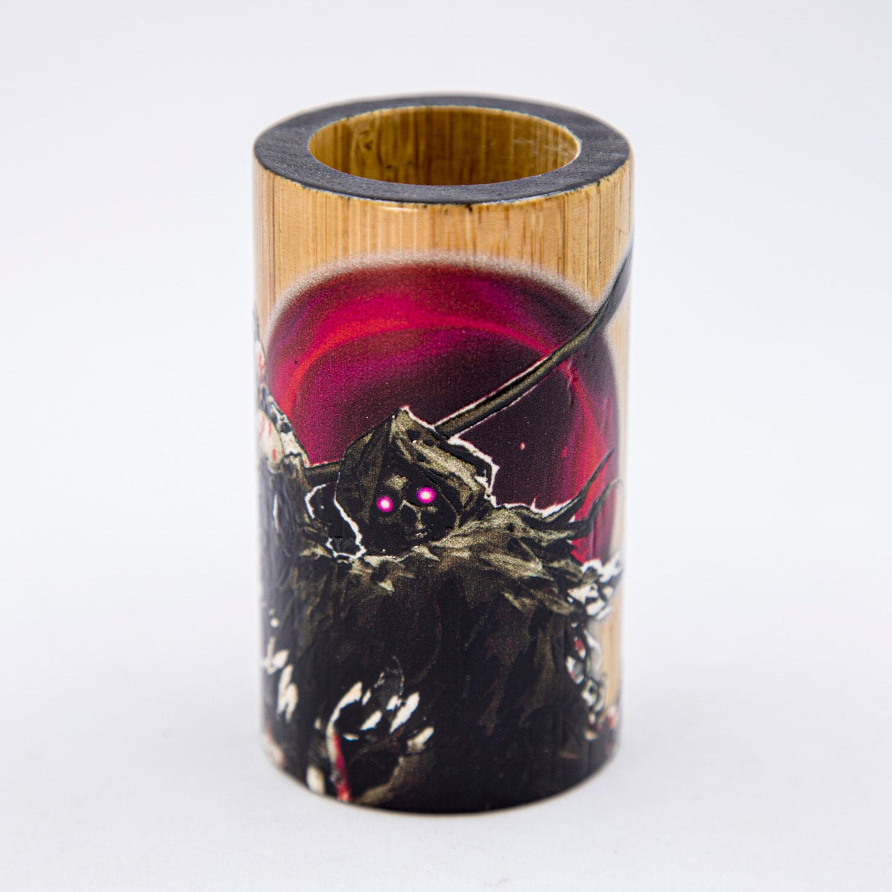 Cylindrical wooden product with a dark design and glowing eyes on a white background