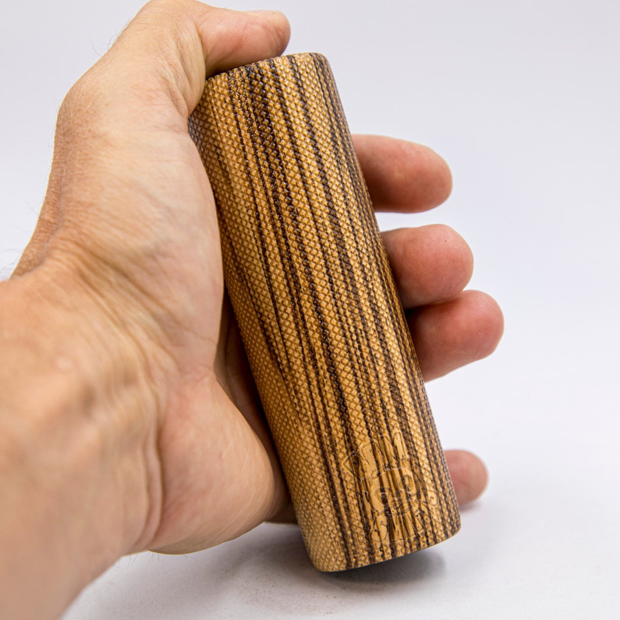 Hand holding a cylindrical wooden object against a white background