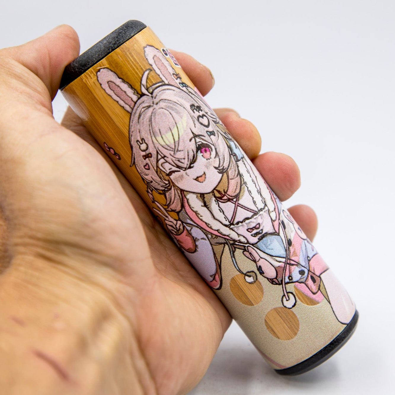 Hand holding a cylindrical product with cartoon character design on a white background